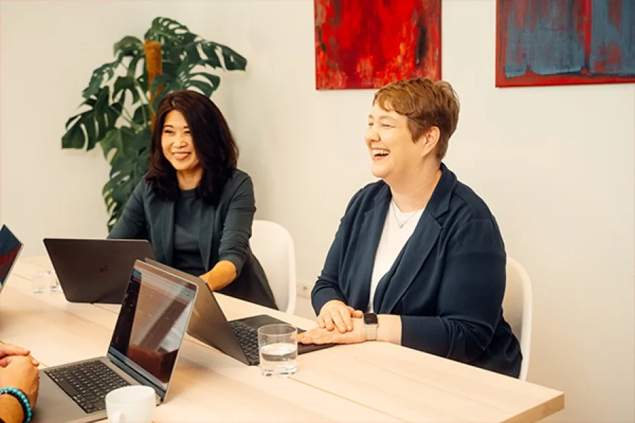 Zwei Kolleginnen aus dem rose-Team im Gespräch am Besprechungstisch